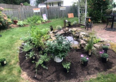 This fun project in Hudson, NH had the crew revisiting and revamping one of our existing gardens! The Excavator dug out 10 yards of poor soil and replaced it with 10 yards of good soil. Last year , in early July, we planted 100 perennials of which half were shade and the others sun loving. These new 80 perennials really made the front side and back yard pond garden quite lovely.